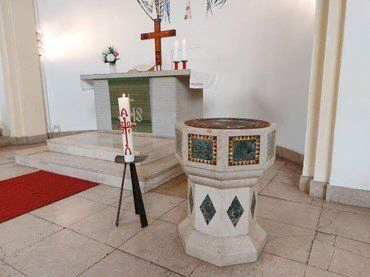 Taufbecken und Altar in einer Kirche.