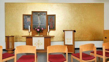 Kleiner Kapelleninnenraum mit Altar und religiösen Symbolen.